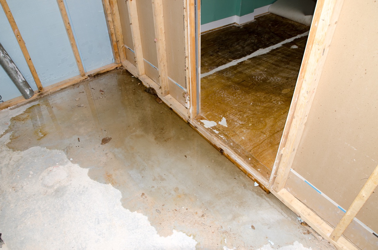 View of a concrete basement floor full of water caused by sewer backflow due to clogged sanitary drain